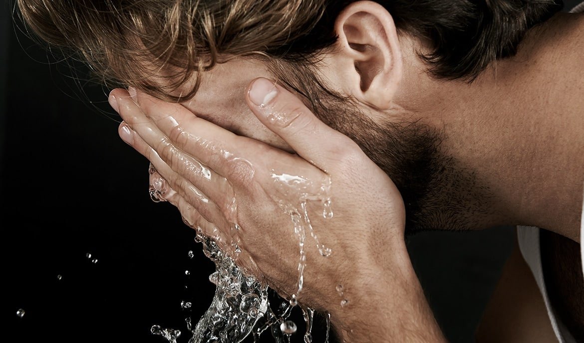 Mann wäscht sich das Gesicht